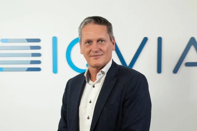 Foto av Stefan Ohlsson framför logotyp