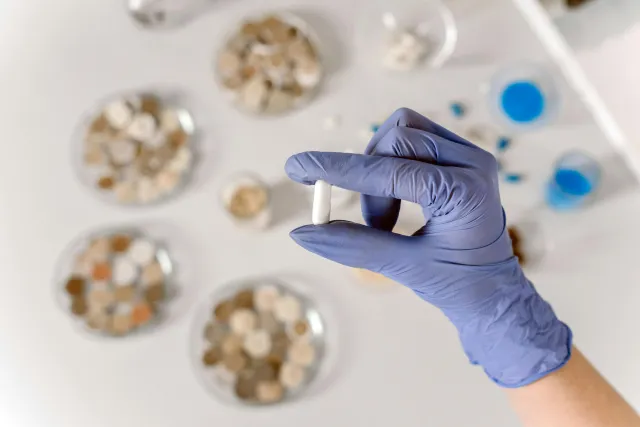 Foto av en hand med handske som håller i labb utrustning